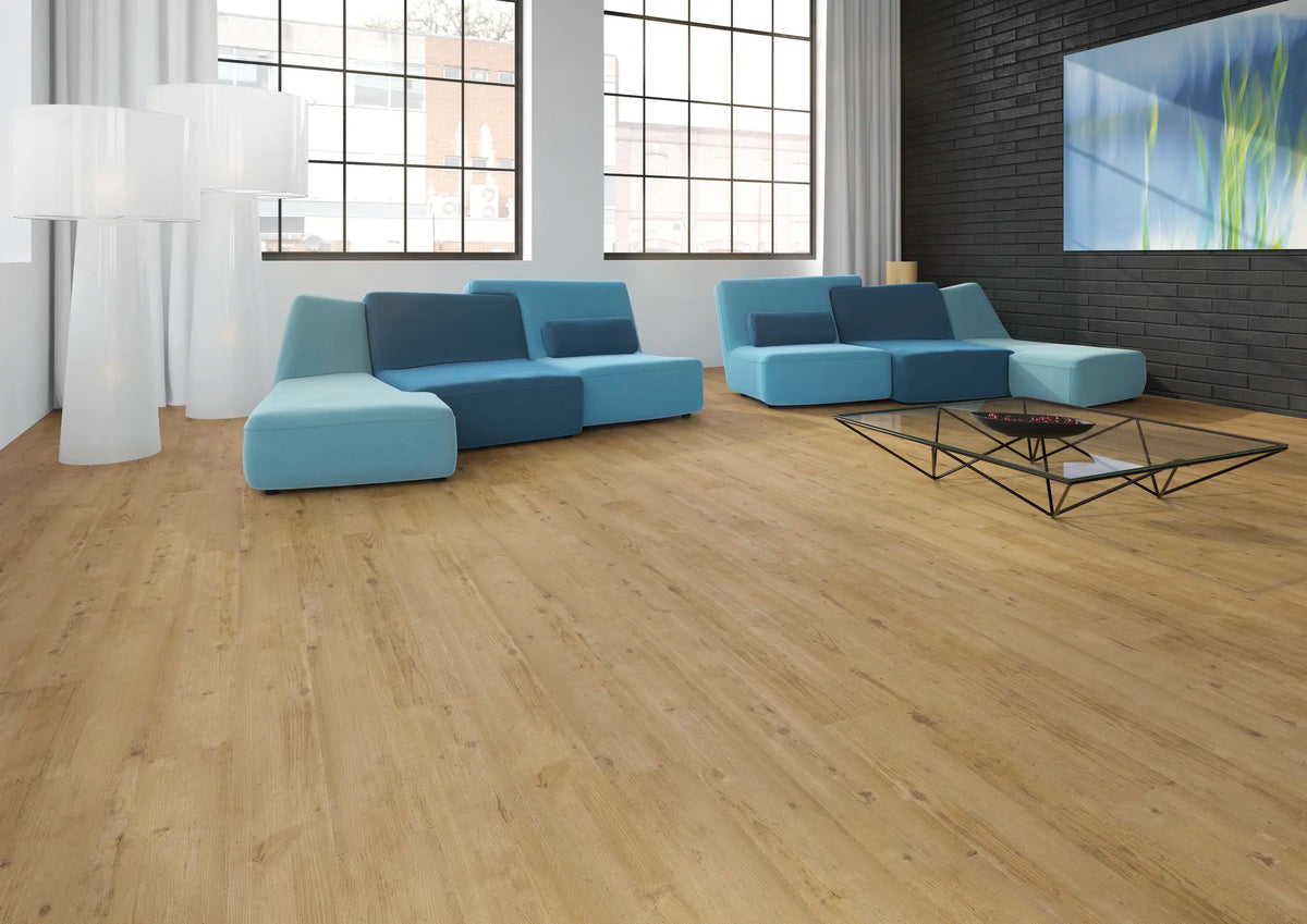 JOKA Design 340 Dryback 2824 Warmy Light Oak Klebevinyl im Wohnraum mit blauen Sitzmöbeln, großen Sprossenfenstern und schwarzer Ziegelwand